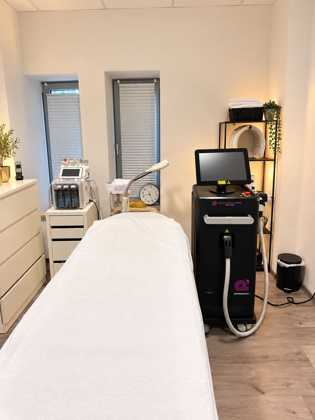 Heller Behandlungsraum mit Liege und Diodenlaser-Gerät